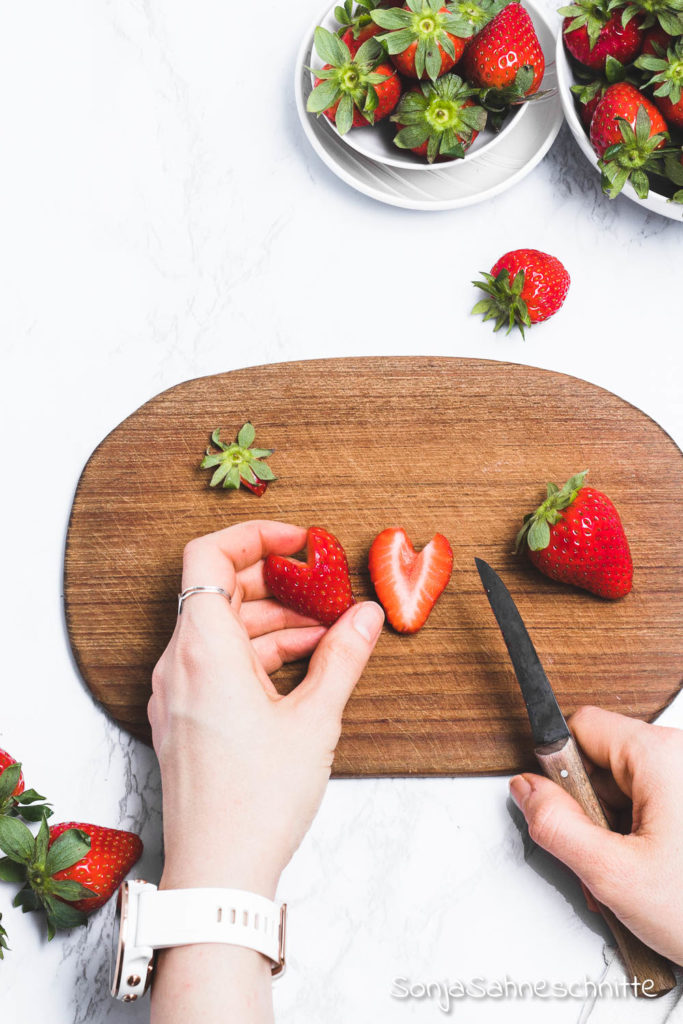 Erdbeer-Herzen: Erdbeeren in Herzform schneiden ist super einfach, schnell gemacht ins unglaublich dekorativ. Egal ob ihr Kuchen, Torten, Desserts oder euer Müsli dekorieren wollt. Die Herzen werdet ihr bestimmt nicht nur zum Muttertag oder am Valentinstag machen. Probiert die 3 Schritte Anleitung doch gleich mal aus. #erdbeeren #deko #süßeSachen #selbermachen #SonjaSahneschnitte